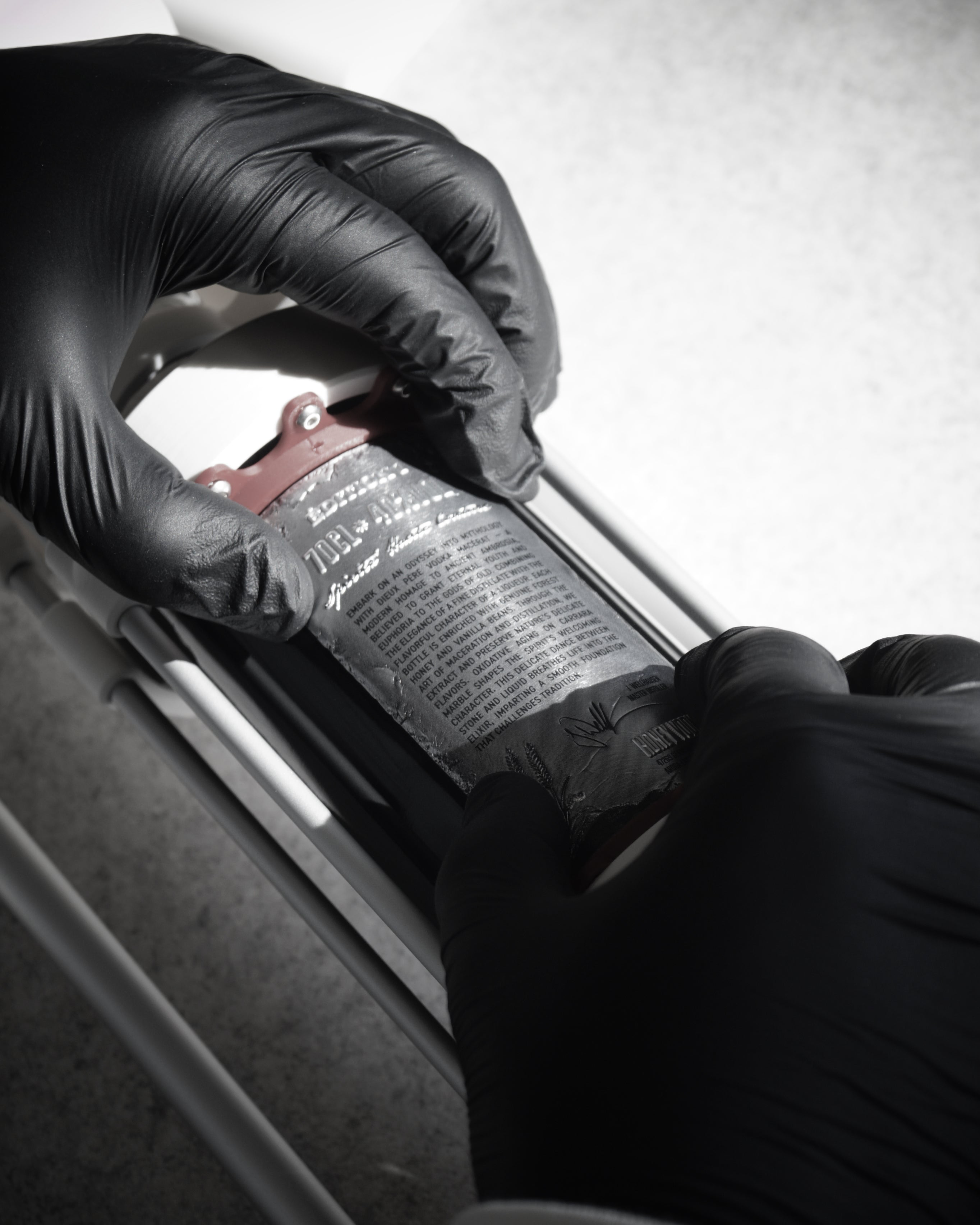 Maison Dieux Père vodka macérat bottle being decorated with its label by hand.