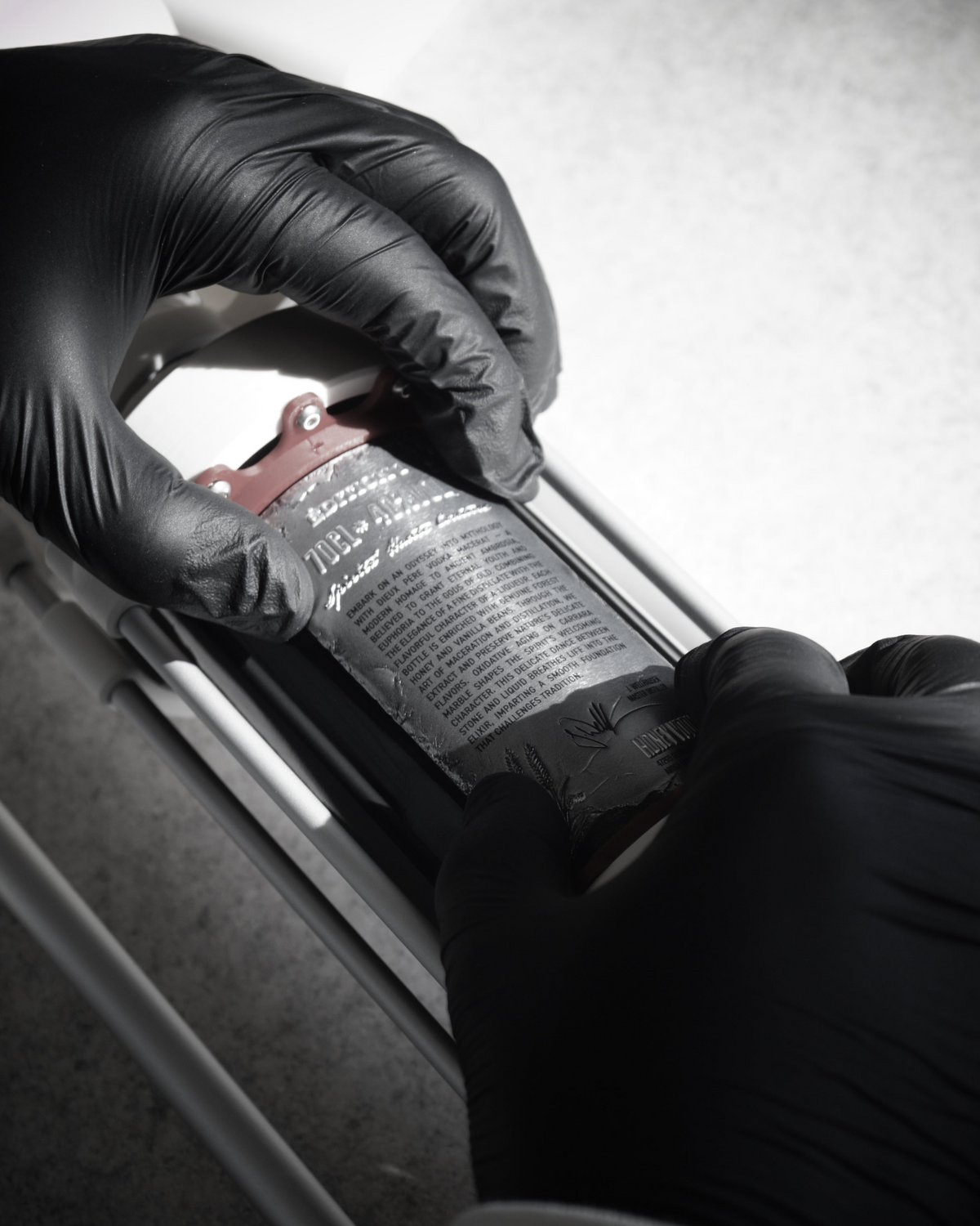 Maison Dieux Père vodka macérat bottle being decorated with its label by hand.